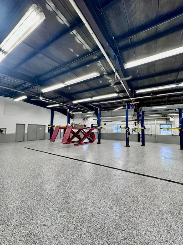 Auto dealership service bay with vehicle lifts over a gray flake epoxy floor — Central New York