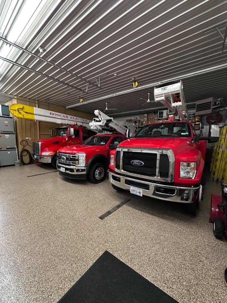 Apparatus bay with red trucks parked on a tan flake epoxy floor that resists fuel and salt — Central New York